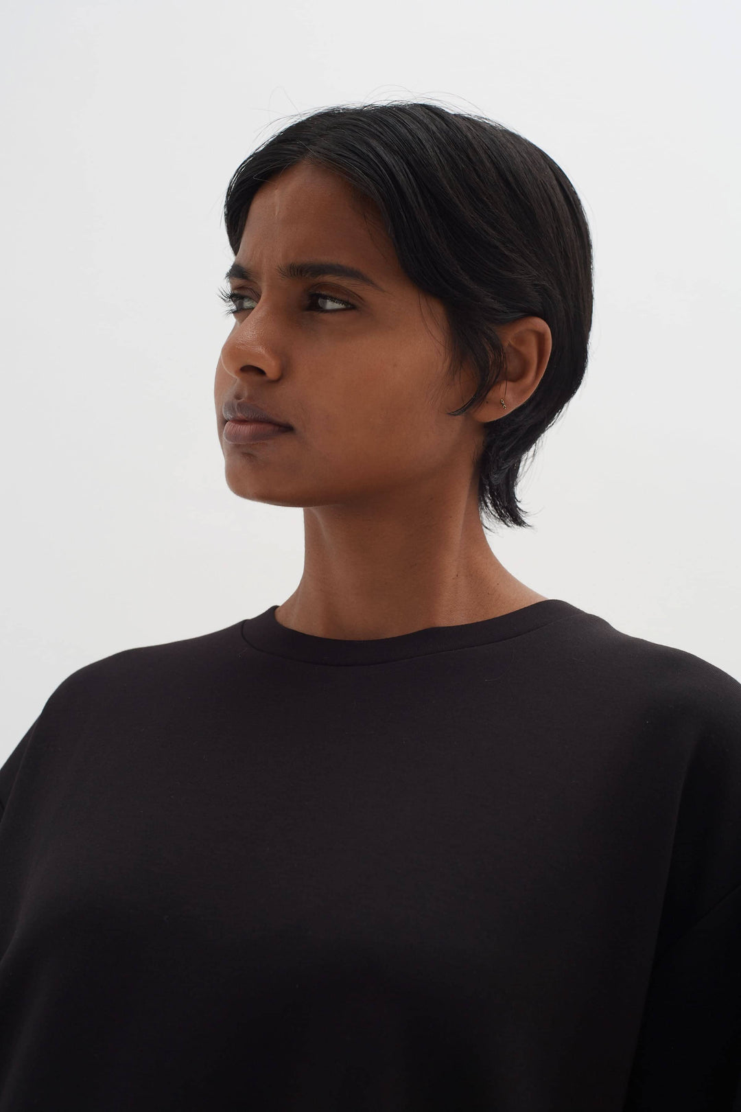 Femme portant un t-shirt ample noir avec des manches 1/2 et une encolure ronde.