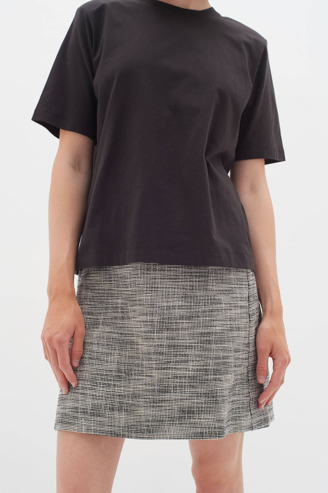 Femme portant une jupe droite à motif de petits carreaux avec un t-shirt noir, idéal pour un look professionnel.