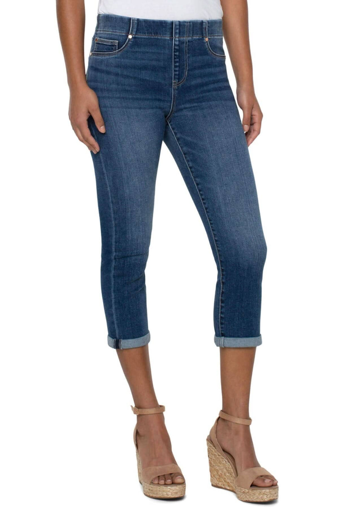 Jeans roulé court en denim bleu, taille haute et poches avant, portés avec des sandales compensées.