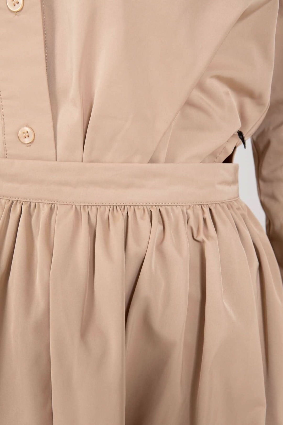 Détails de la jupe longue beige avec plis et ceinture, offrant une silhouette élégante et confortable.