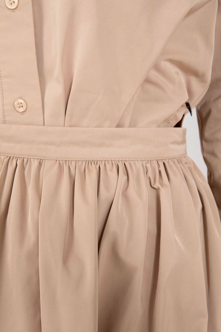 Détails de la jupe longue beige avec plis et ceinture, offrant une silhouette élégante et confortable.
