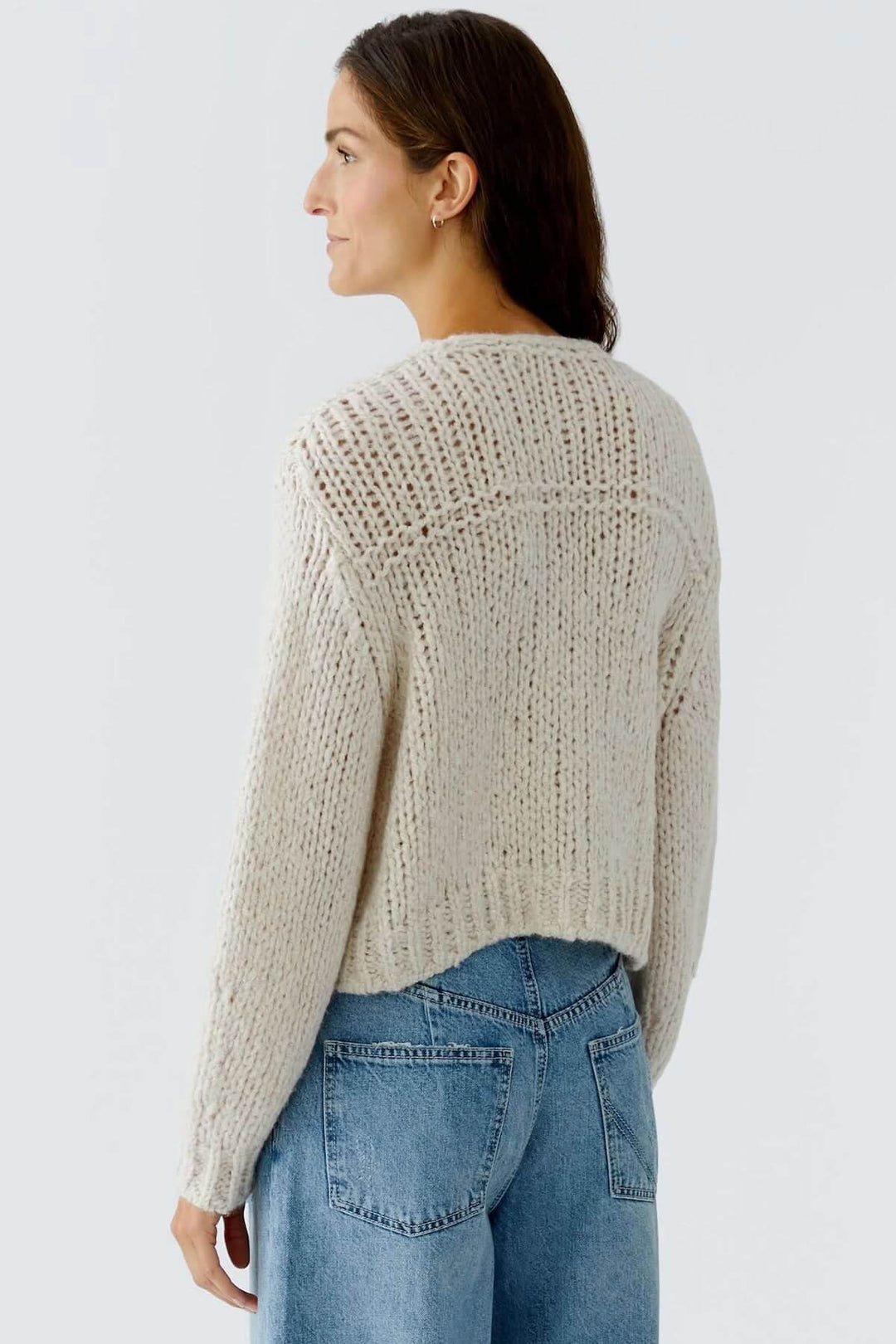 Veste en tricot épais à boutons bijoux, maille ajourée, vue arrière sur mannequin portant un pantalon en denim.