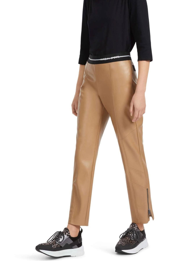 Pantalon en cuir beige SOFIA avec ceinture élastiquée et ourlet fendu, associé à des sneakers stylées.