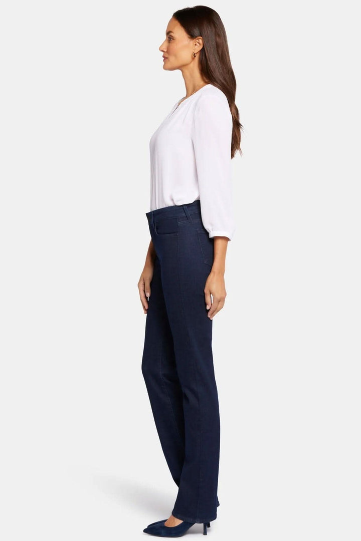 Femme portant un jean droit Marilyn, coupe flatteuse, style classique, bel ajustement avec un top blanc.