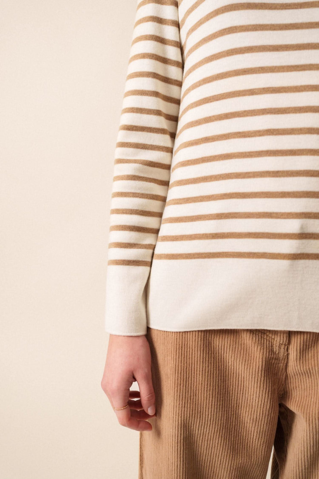 Chandail Bregancon R avec rayures beiges, porté avec un pantalon en velours pour un look automnal décontracté.