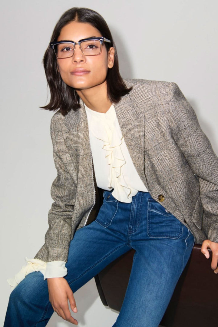 Femme portant un blazer à carreaux avec blouse blanche et jeans, ajoutant une touche chic et moderne.