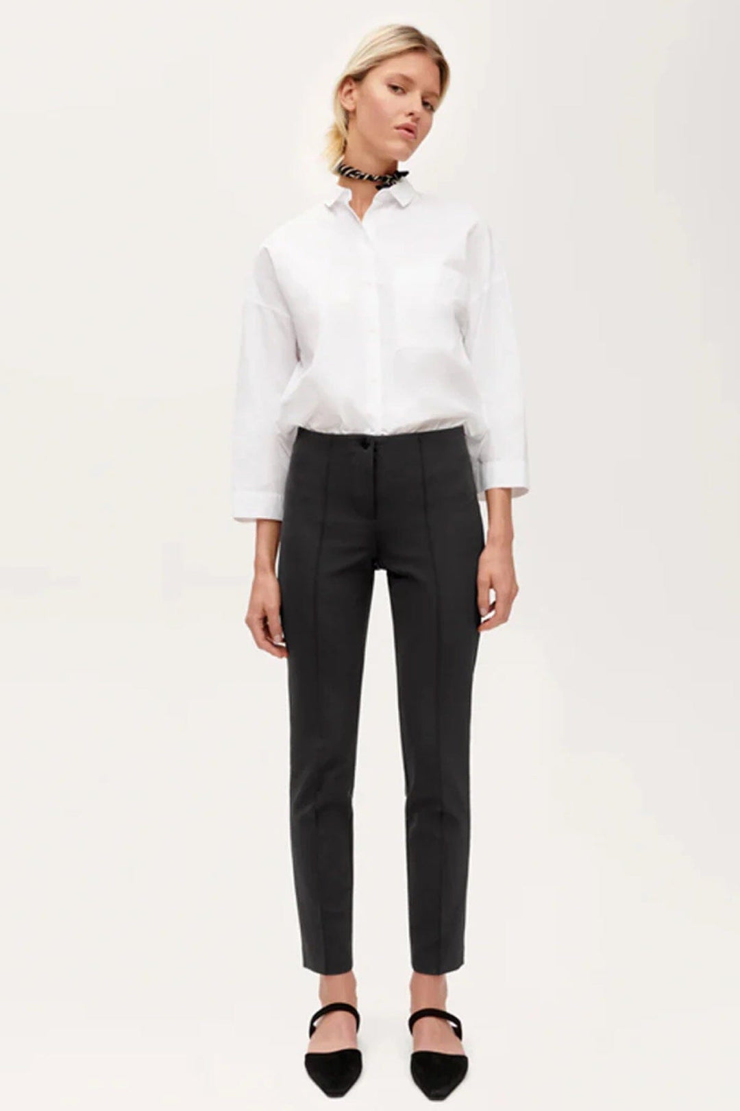 Pantalon slim Ros de Cambio, coupe courte, tissu techno, taille élastique, style épuré, porté avec chemise blanche.