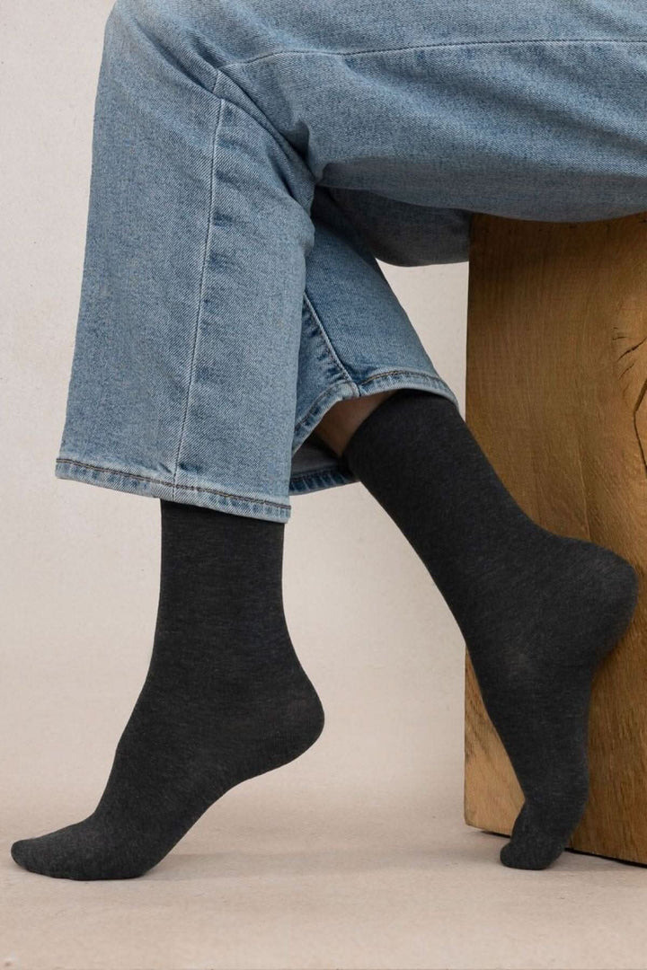 Chaussettes en coton noir porté avec un pantalon en denim, offrant confort et style.
