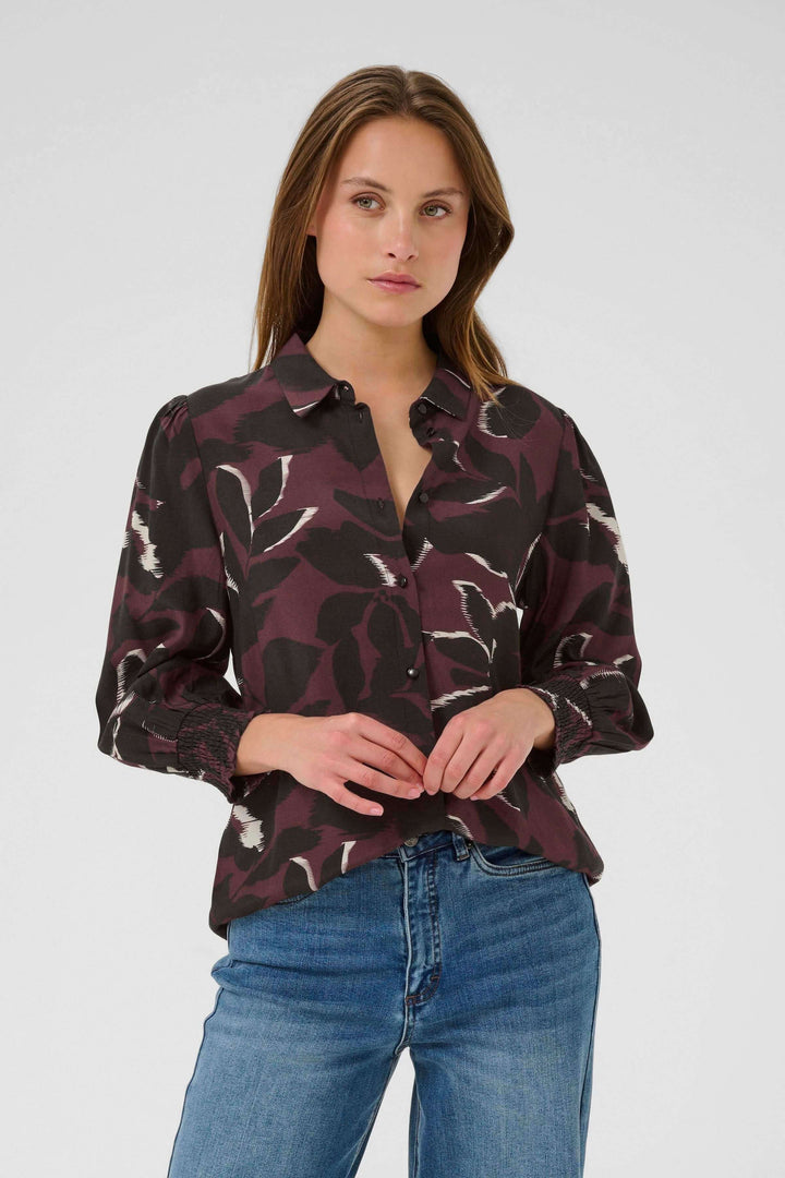 Femme portant une chemise Mille imprimée à manches longues et poignets smockés avec un col classique et un imprimé graphique moderne.