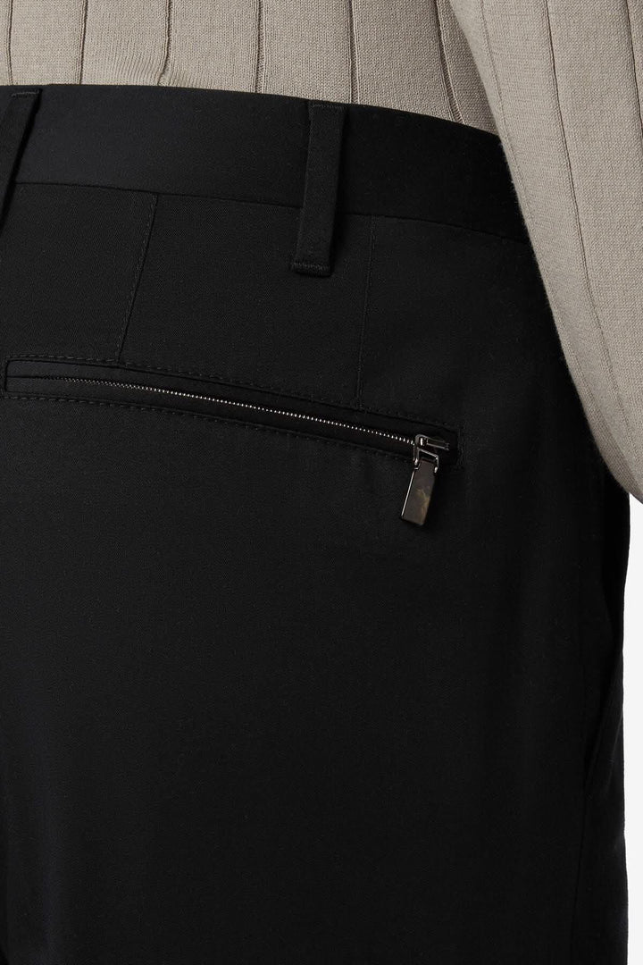 Détail du pantalon habillé en coton noir, avec poche zippée au dos pour un style contemporain et pratique.