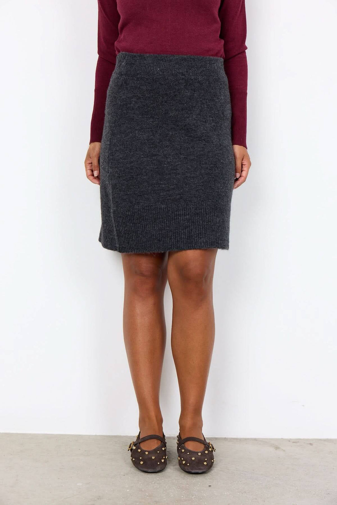 Femme portant une jupe crayon en laine avec une bande élastique à la taille, parfaite pour un look élégant et confortable.