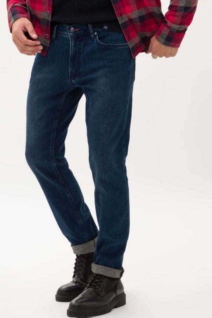 Jean Chuck pour homme, coupe moderne en denim bleu, porté avec des bottes et une chemise à carreaux.