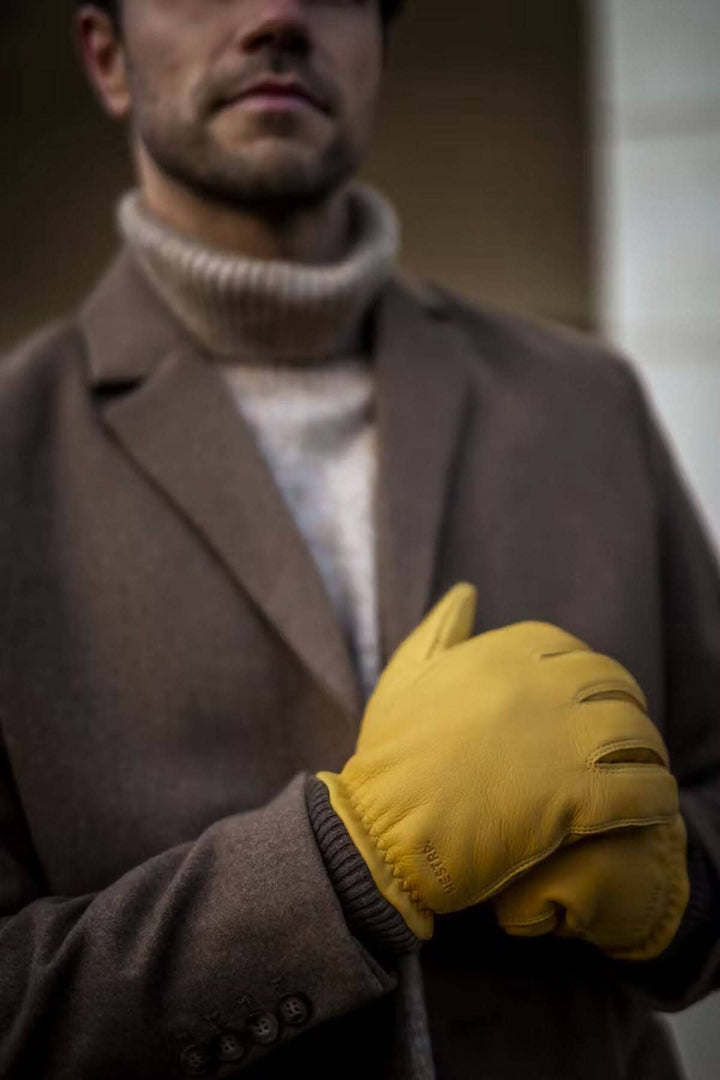 Gant de cuir Tore en peau de cerf, homme portant des gants jaunes avec manteau élégant en hiver.