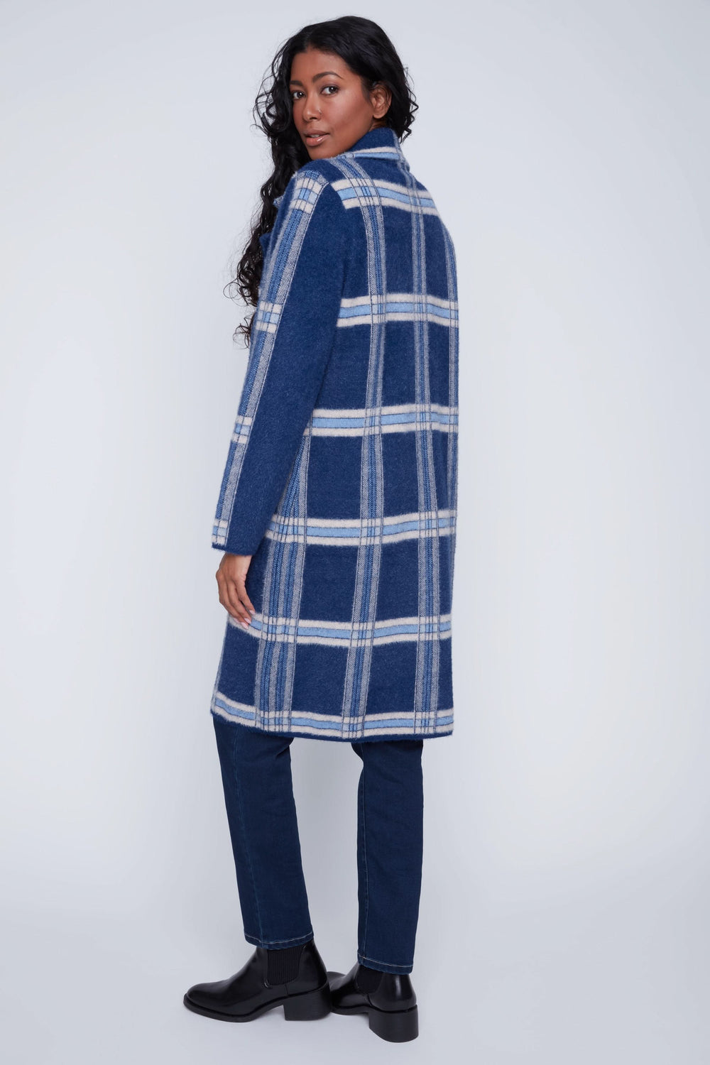 Manteau long à carreaux bleus, coupe droite, col à revers, porté avec pantalon ajusté pour un look chic.