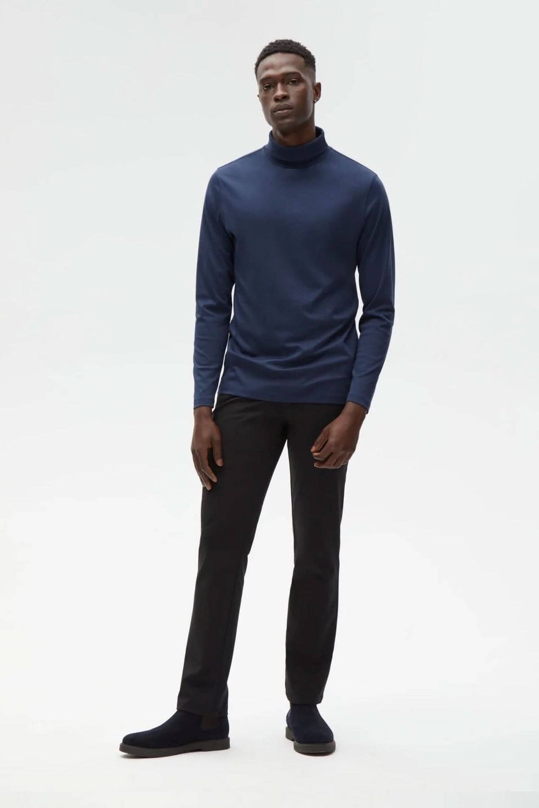 Homme portant un col roulé de coton Georgia en bleu, associé à un pantalon noir et des chaussures confortables.