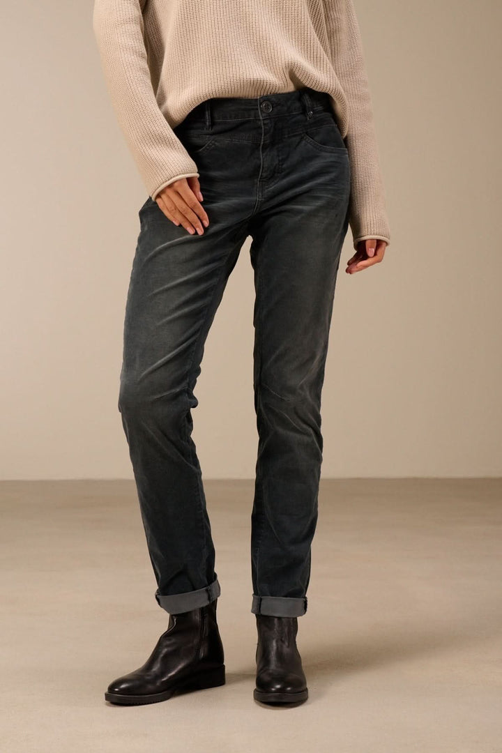Pantalon en velours côtelé coupe ajustée pour un look moderne et décontracté, porté avec des bottines noires sur un fond neutre.