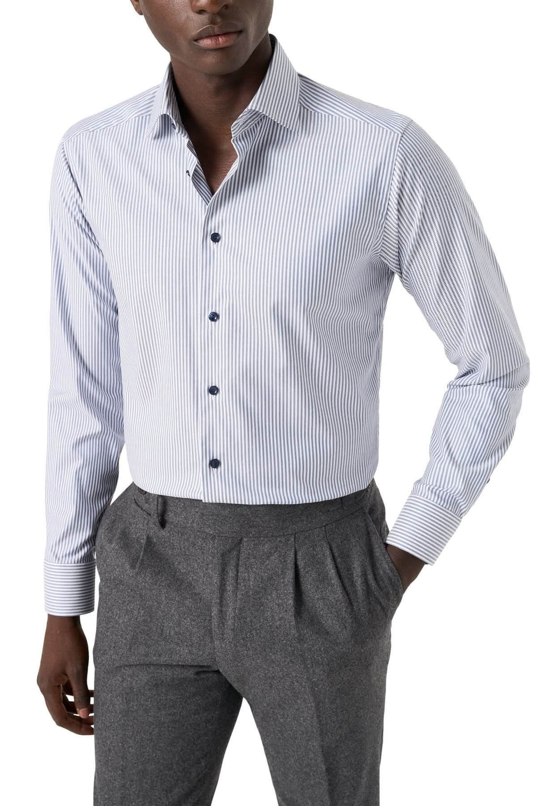 Chemise lignée élégante et intemporelle à rayures bleu marine, col cutaway, portée par un homme avec pantalon gris.