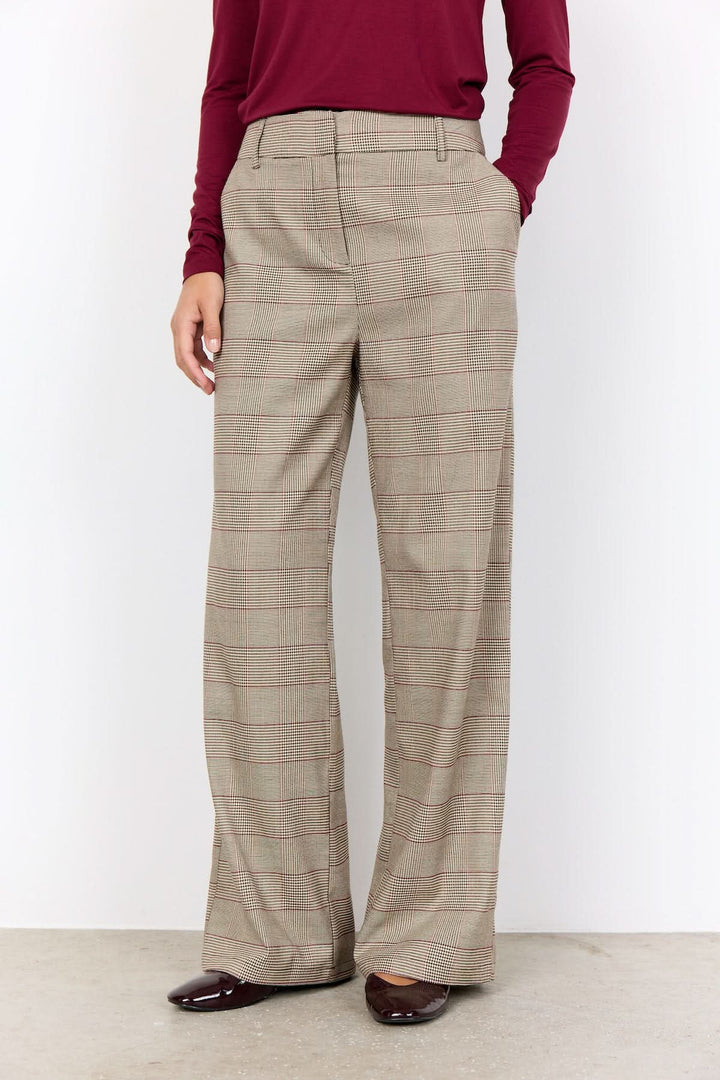 Pantalon à carreaux prince-de-galles avec coupe large, porté avec un haut rouge, style bureau élégant.