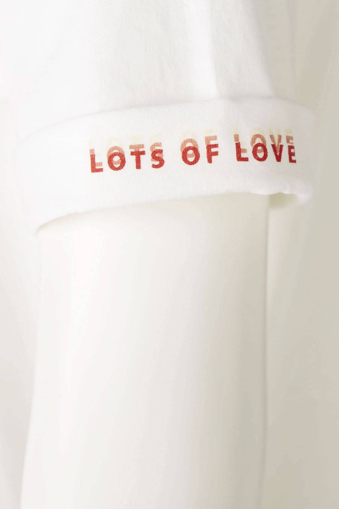T-shirt blanc avec inscription 'LOTS OF LOVE' sur la manche, élégant et décontracté.