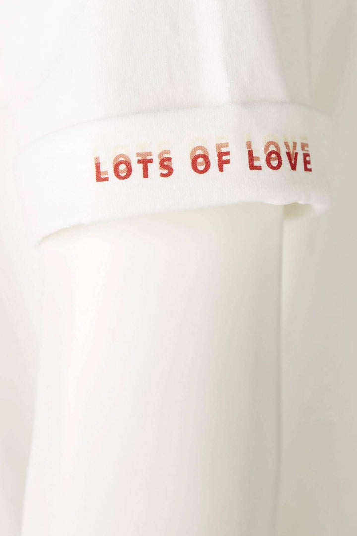 T-shirt blanc avec inscription 'LOTS OF LOVE' sur la manche, élégant et décontracté.