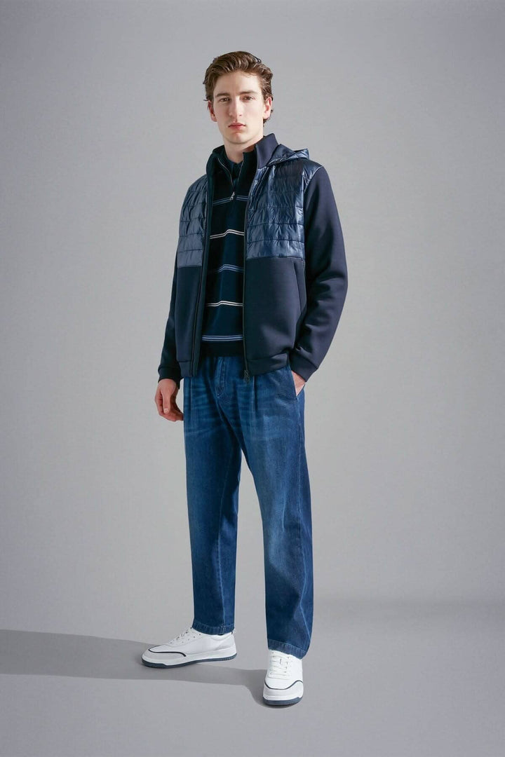 Homme portant un chandail ligné à demi-zip, associé à un blouson, jeans et chaussures blanches.