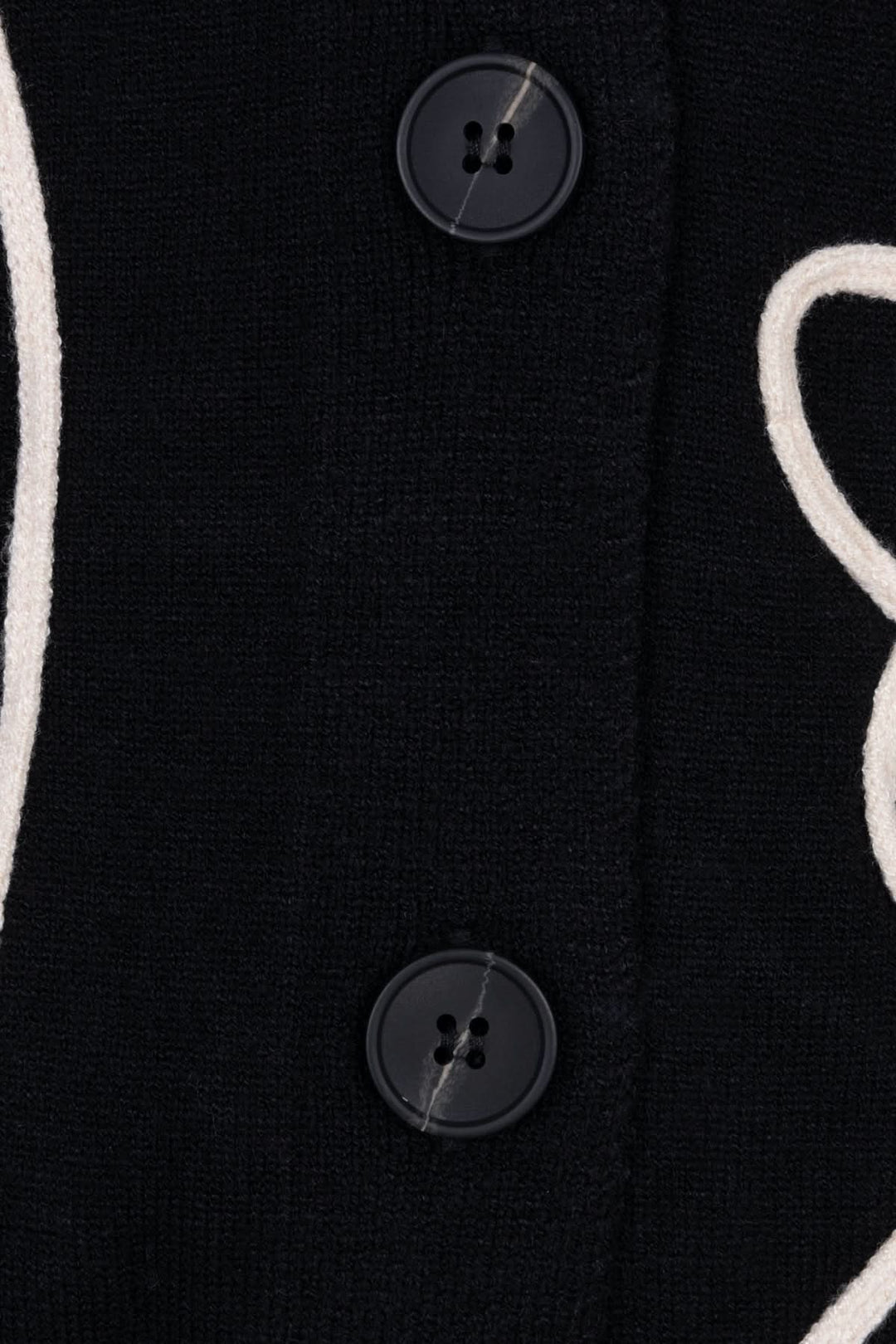 Zoom sur les boutons d'un cardigan graphique en maille souple avec motif linéaire contrasté.