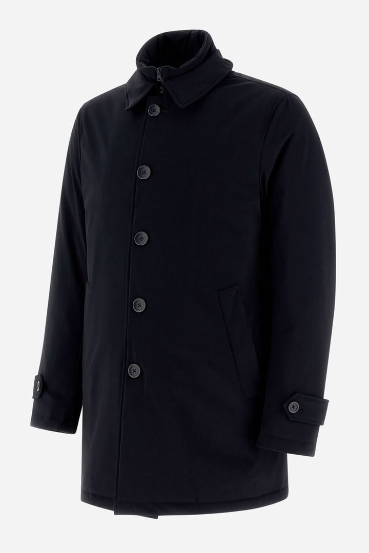 Trench coat noir en tissu extensible, résistant à l'eau, avec boutonnière et poches latérales.