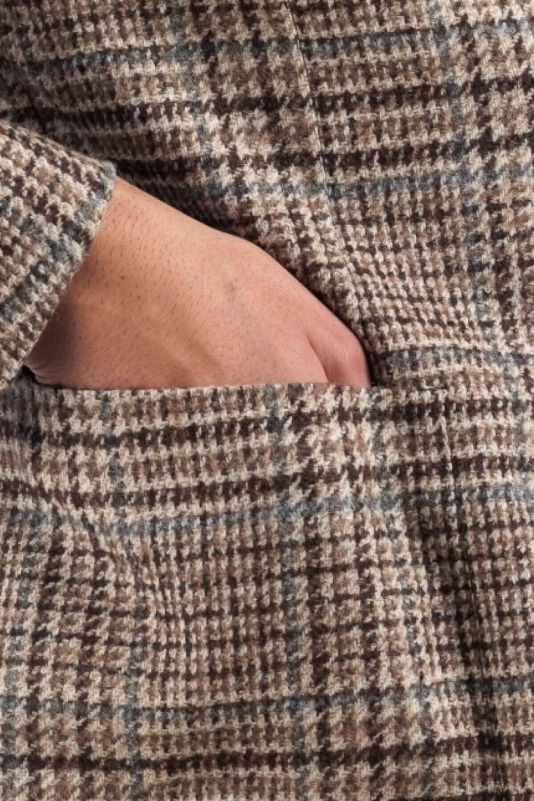 Détail d'un veston à motif pays de galles avec une main insérée dans la poche.