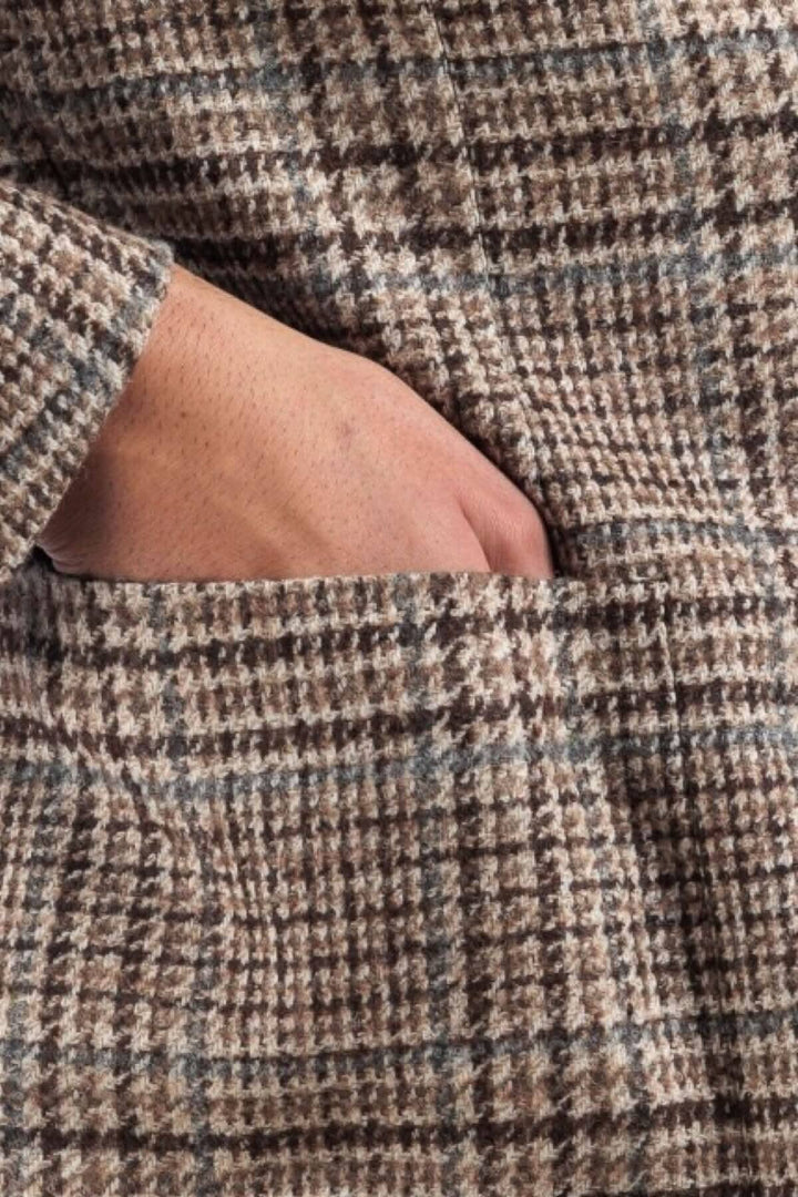 Détail d'un veston à motif pays de galles avec une main insérée dans la poche.