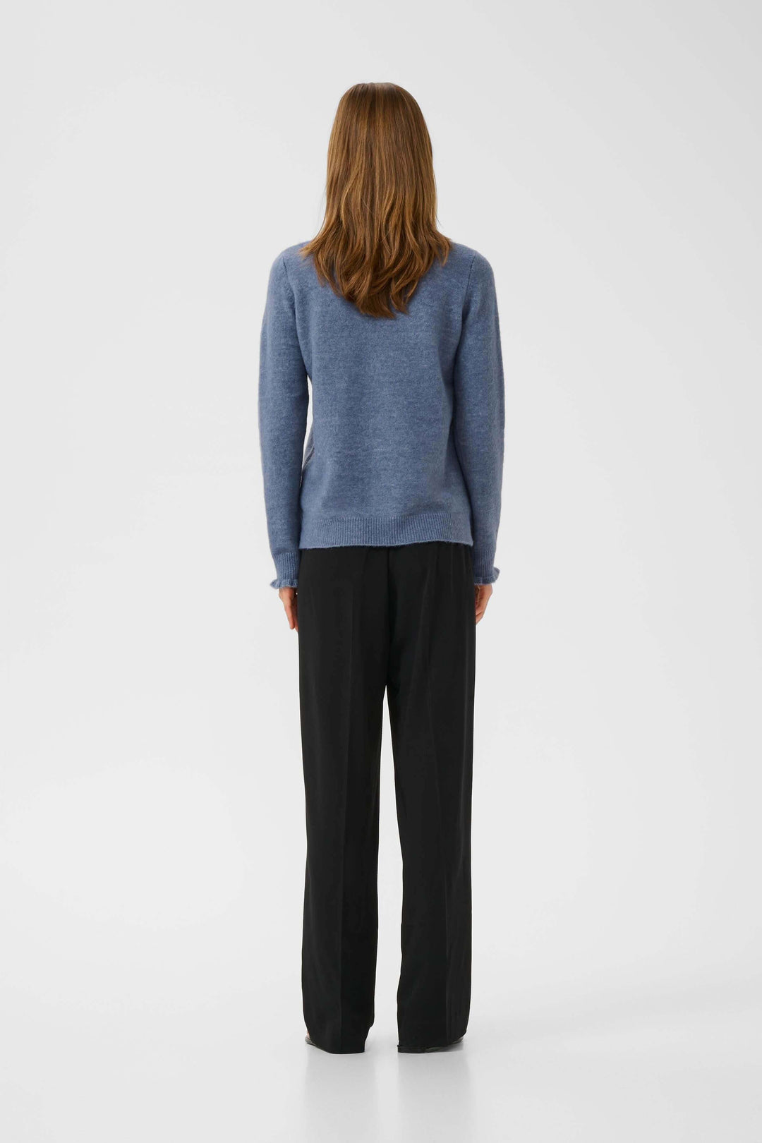 Femme de dos portant un tricot Guni à col montant froncé et un pantalon fluide, style chic décontracté.