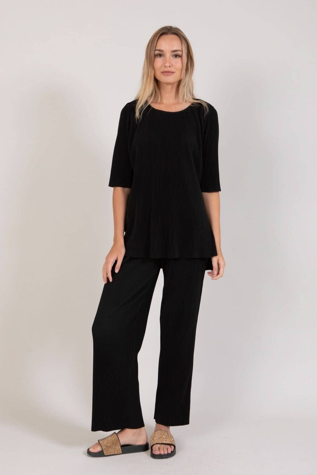 Modèle portant un pantalon ample noir avec t-shirt chic assorti, style décontracté et élégant.