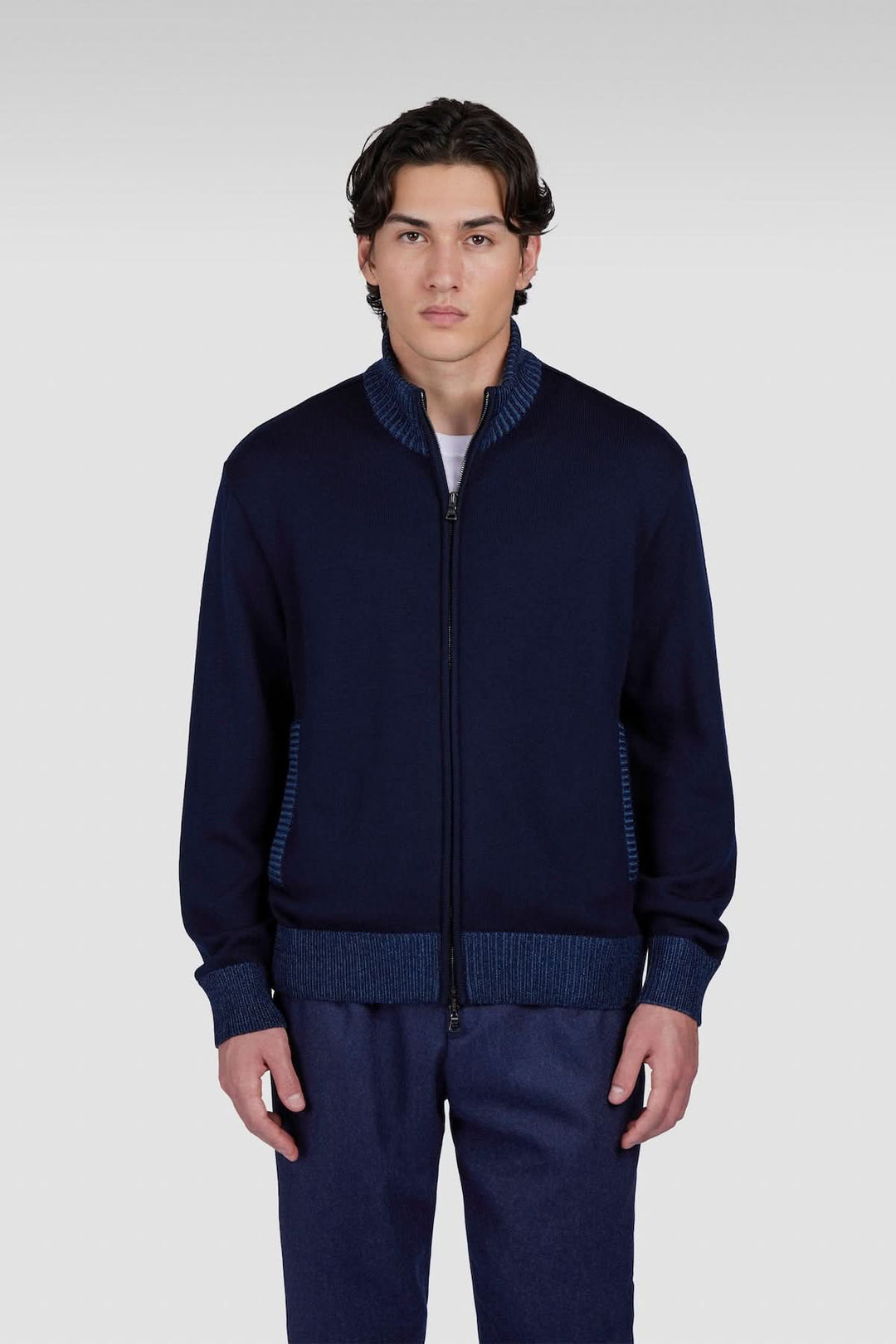 Cardigan à fermeture éclair bleu marine avec col structuré et détails contrastés, porté par un homme.