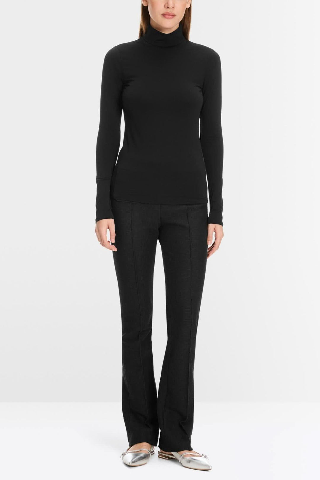 Chandail noir à col roulé et pantalon noir élégant, look moderne et ajusté pour un style chic.