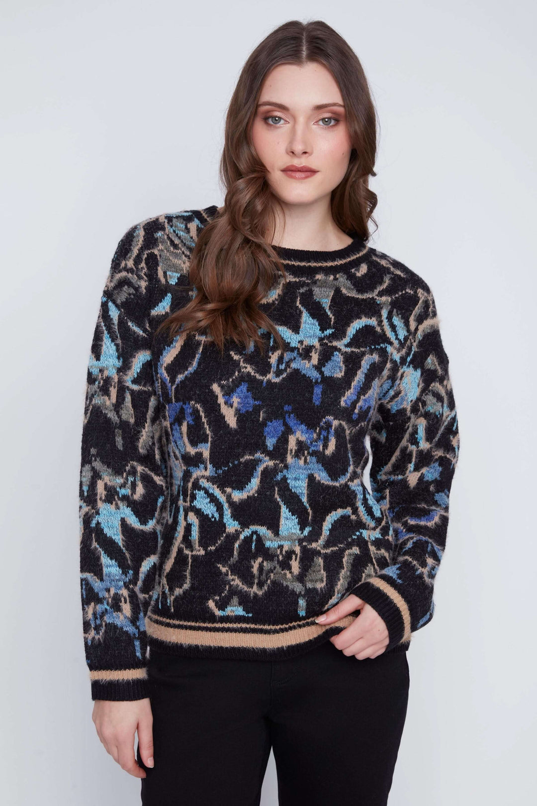 Tricot à manches longues avec motif abstrait multicolore, coupe droite et finition côtelée, porté avec pantalon noir.