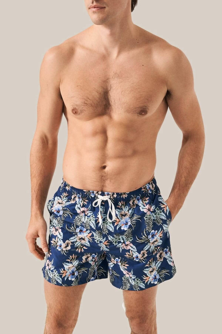 Homme portant un maillot de bain fleuri en polyester, à séchage rapide, avec cordon de serrage et poche zippée.