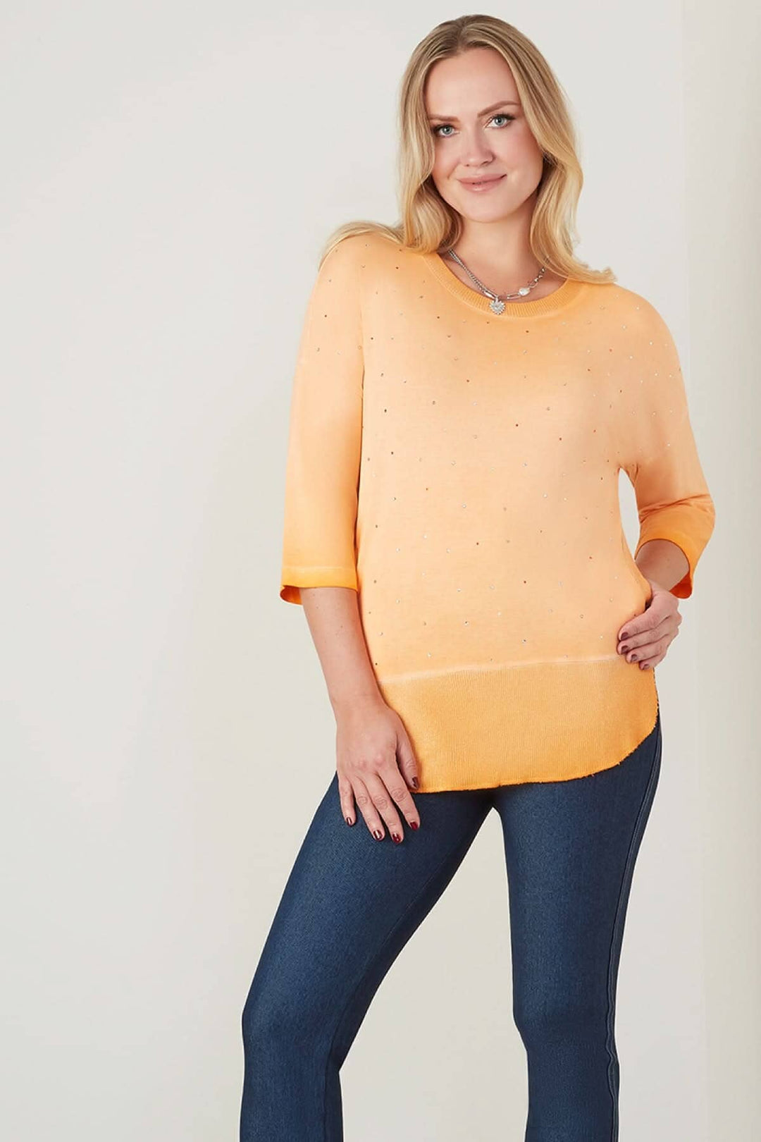 T-shirt long orange avec strass, manches 3/4 et poches latérales pour un style élégant et fluide.