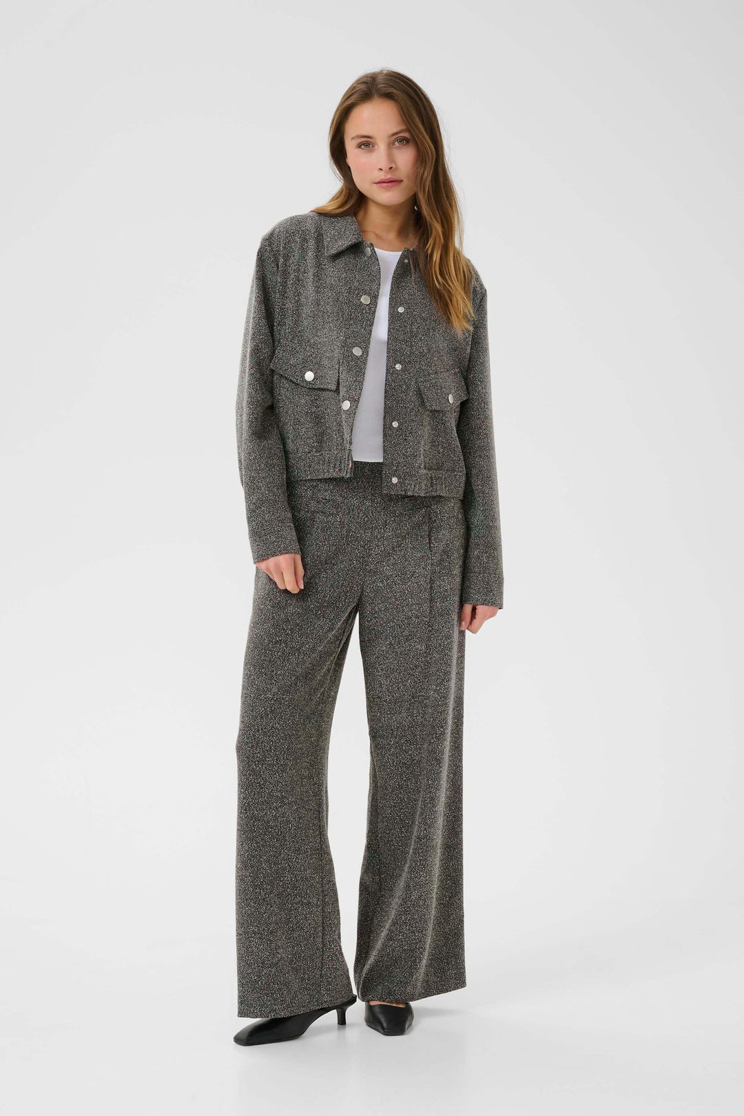 Femme portant le Manteau Alba court à poches à rabat et boutons contrastants, avec un ensemble coordonné élégant et moderne.