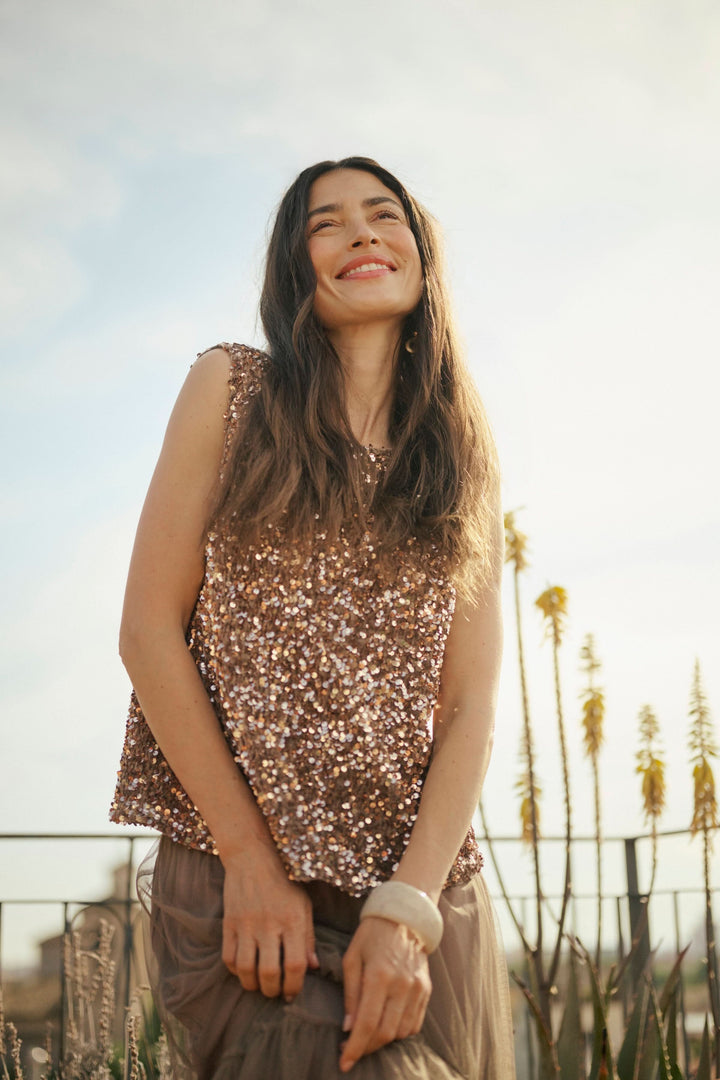 Femme souriante portant un haut à paillettes roses, idéal pour des occasions festives.