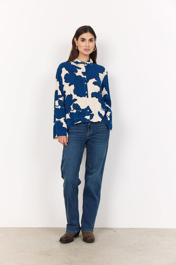 Chemise floral oversize bleue et blanche portée avec un jean taille haute pour un style chic.