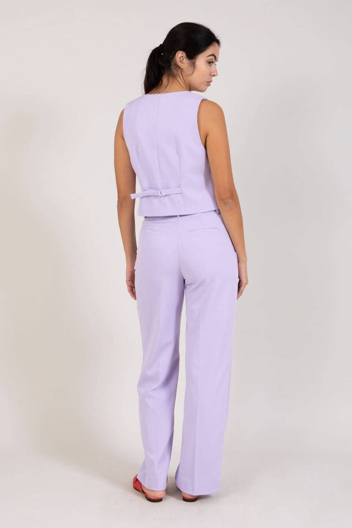 Femme portant un pantalon jambes larges lilas avec un top assorti, vue de dos.