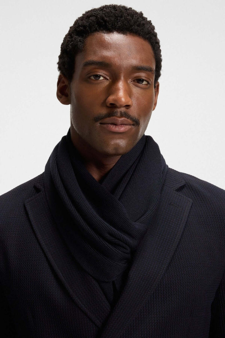 Homme portant foulard de laine vierge Boss en maille Raschel élégante, s'harmonisant avec le manteau pour un look hivernal raffiné.