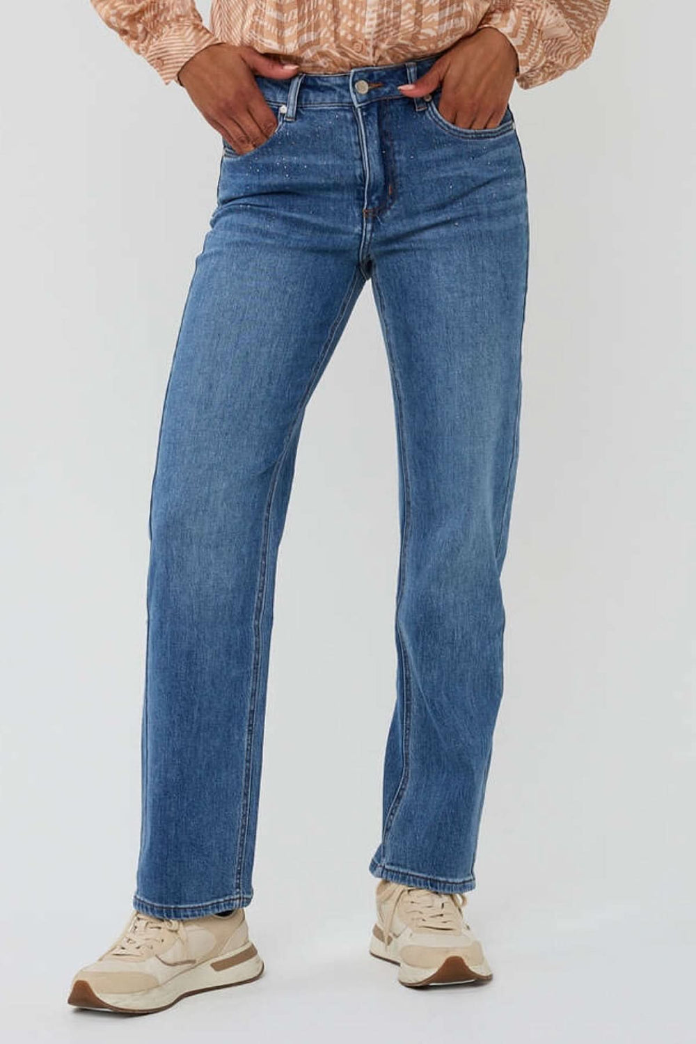 Jean à coupe droite en denim bleu, avec détails scintillants, porté avec un haut stylé.