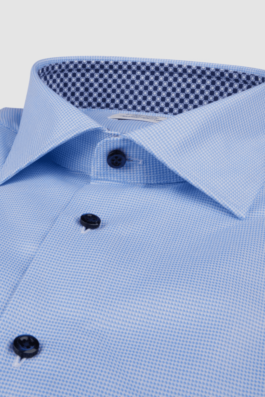 Chemise en sergé bleu avec col contrasté à motif, boutons noirs et détails élégants.