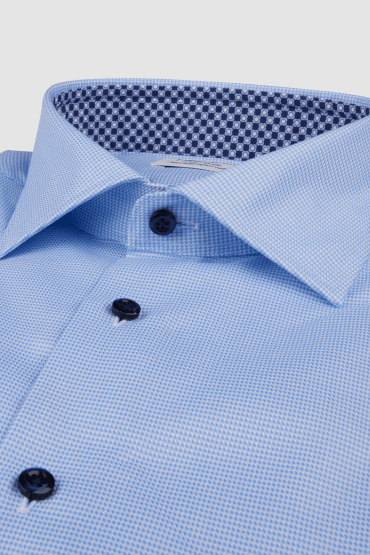 Chemise en sergé bleu avec col contrasté à motif, boutons noirs et détails élégants.