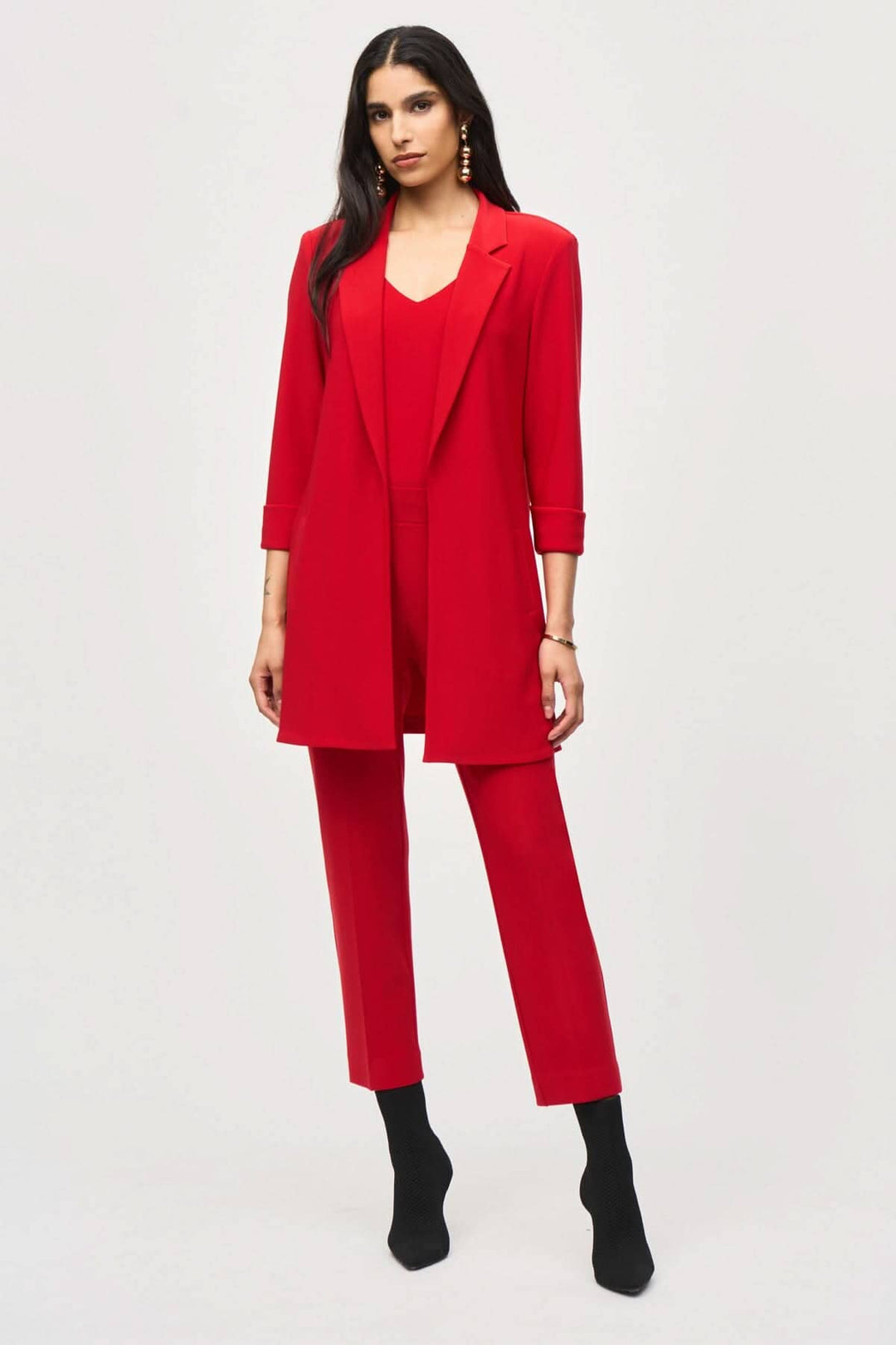 Veston long rouge élégant avec col cranté et manches trois-quarts, porté avec un pantalon assorti.