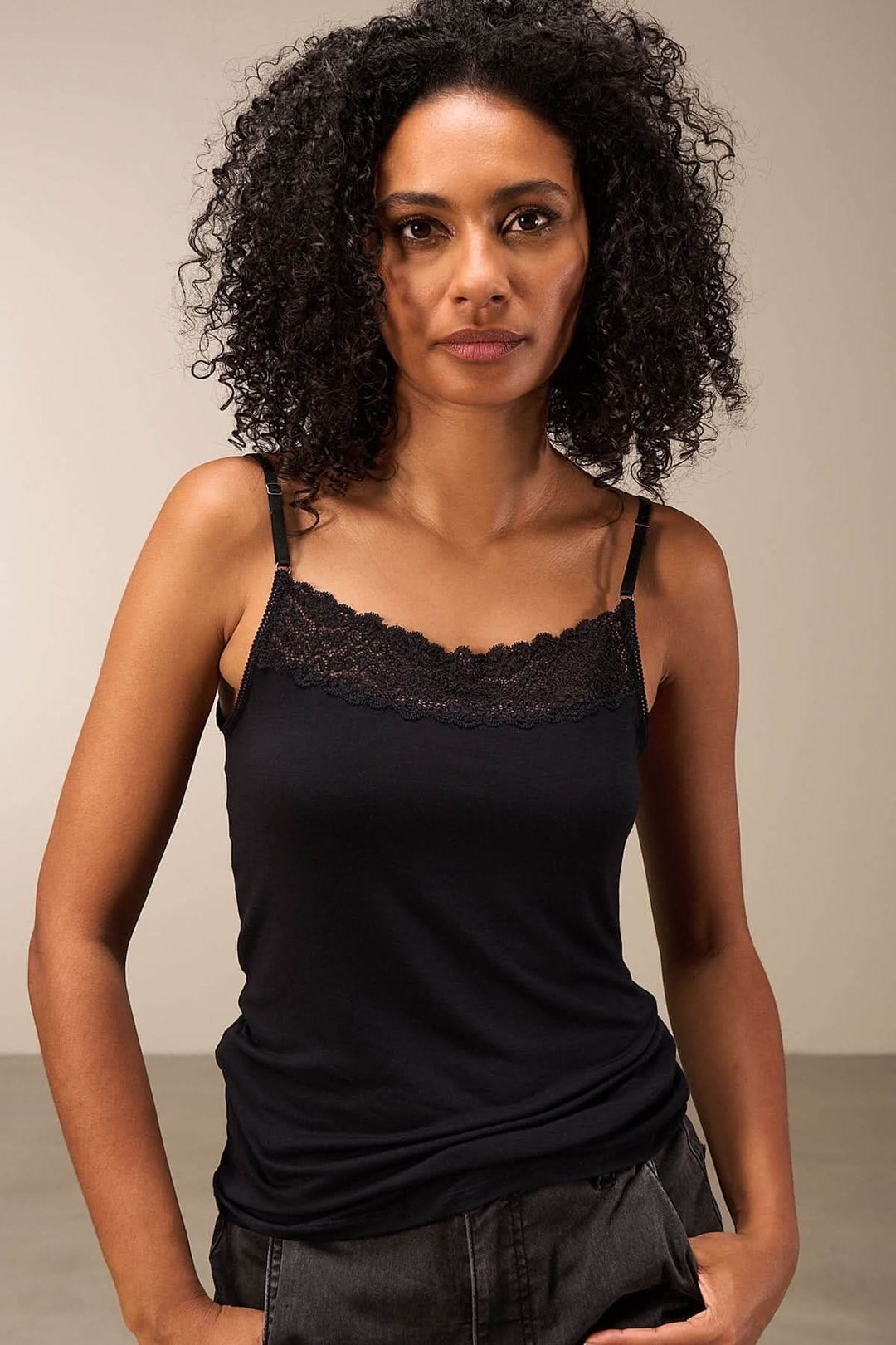 Camisole noire avec dentelle, fines bretelles, coupe ajustée pour un look élégant et confortable.