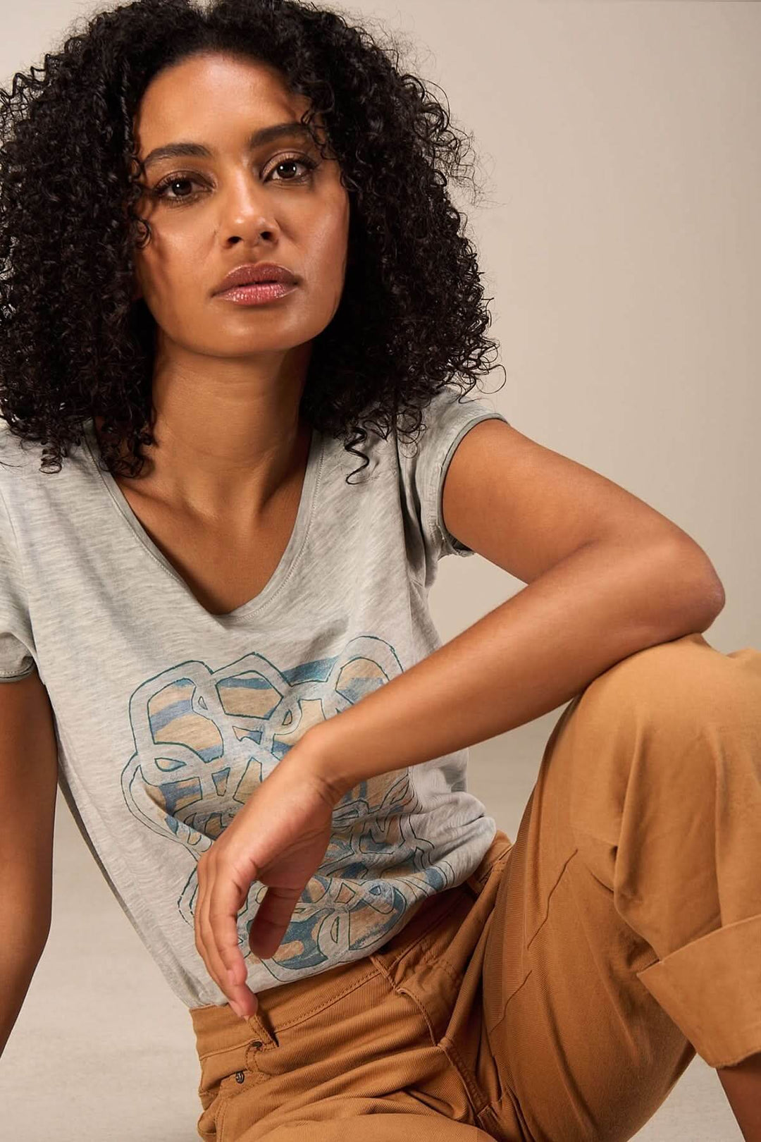 T-shirt imprimé artistique gris à manches courtes, style décontracté porté avec un pantalon beige.