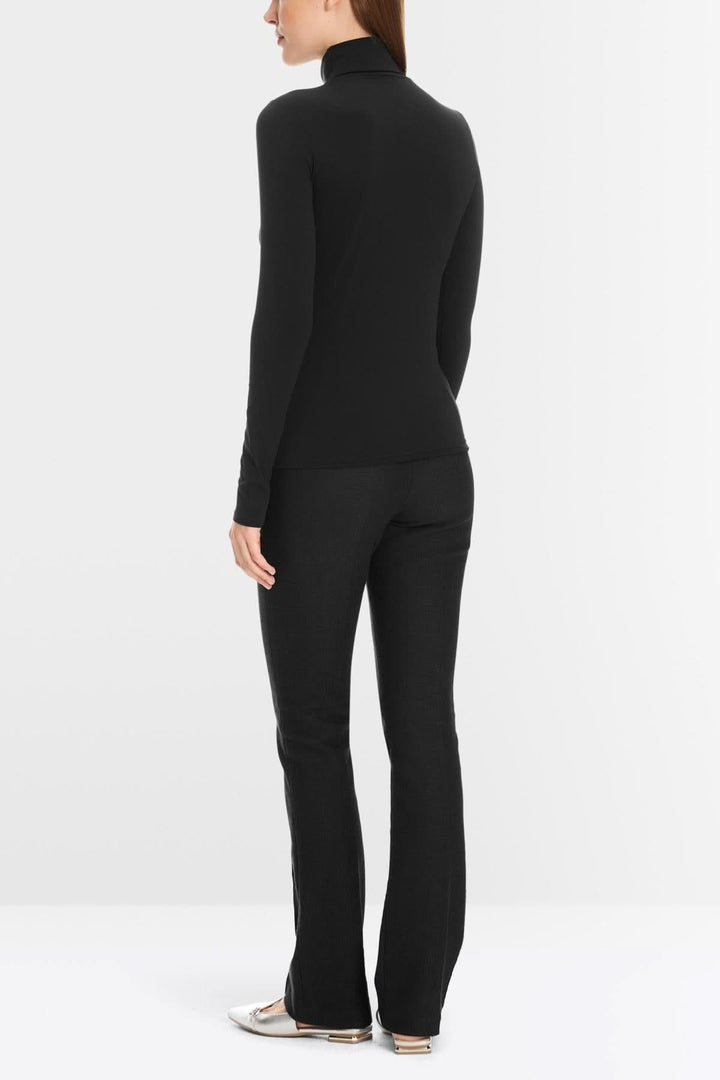 Femme vue de dos portant un chandail à col roulé noir avec un pantalon assorti, mettant en avant un style élégant et confortable.