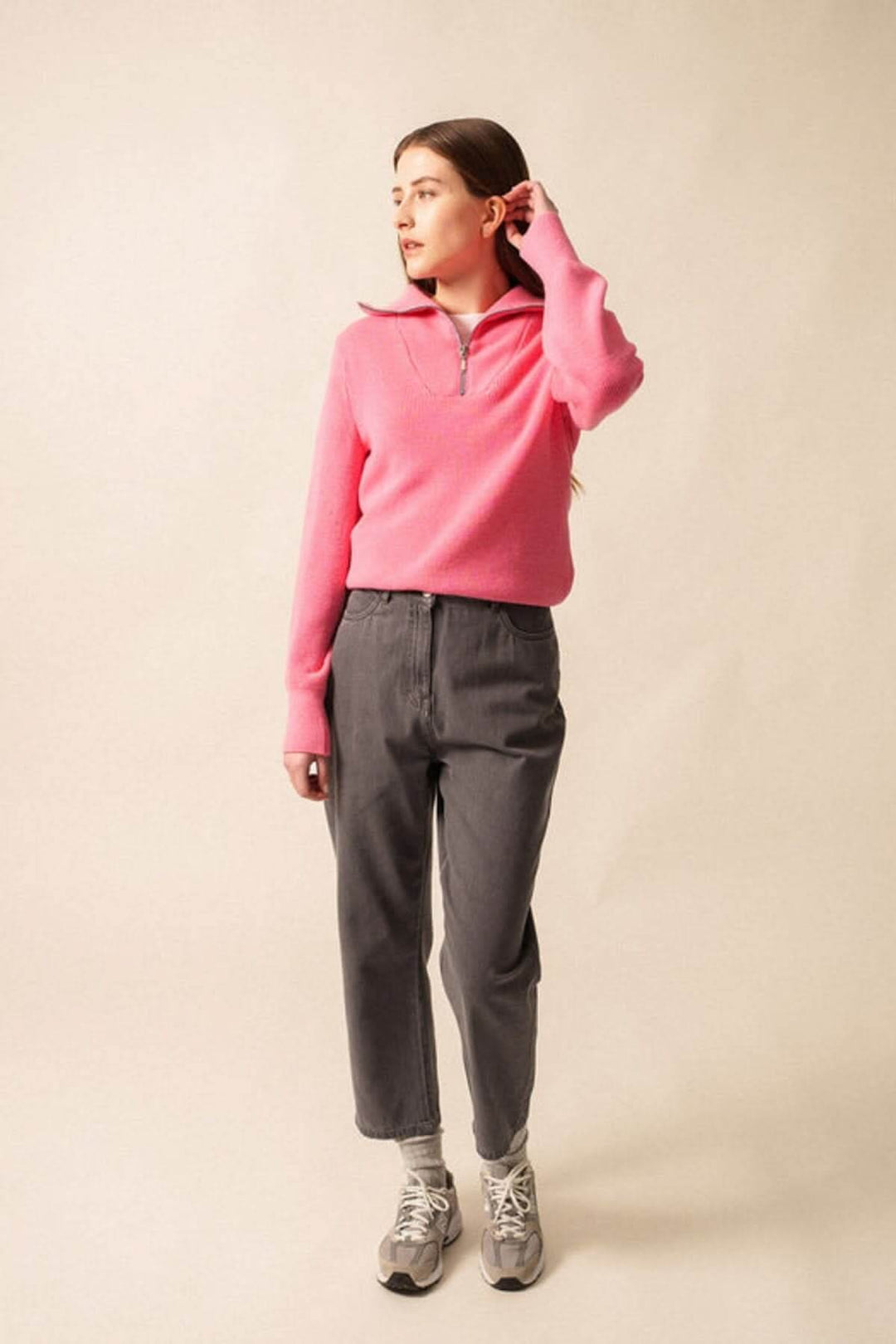 Modèle portant le Tricot col montant SALLANCHES en rose avec manches longues et col camionneur, devant fond neutre.