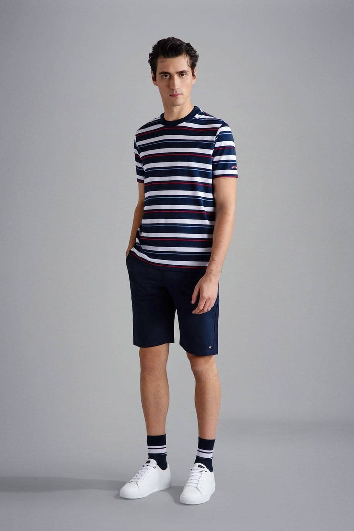 Homme portant un t-shirt ligné multicolore avec shorts, look décontracté et moderne.